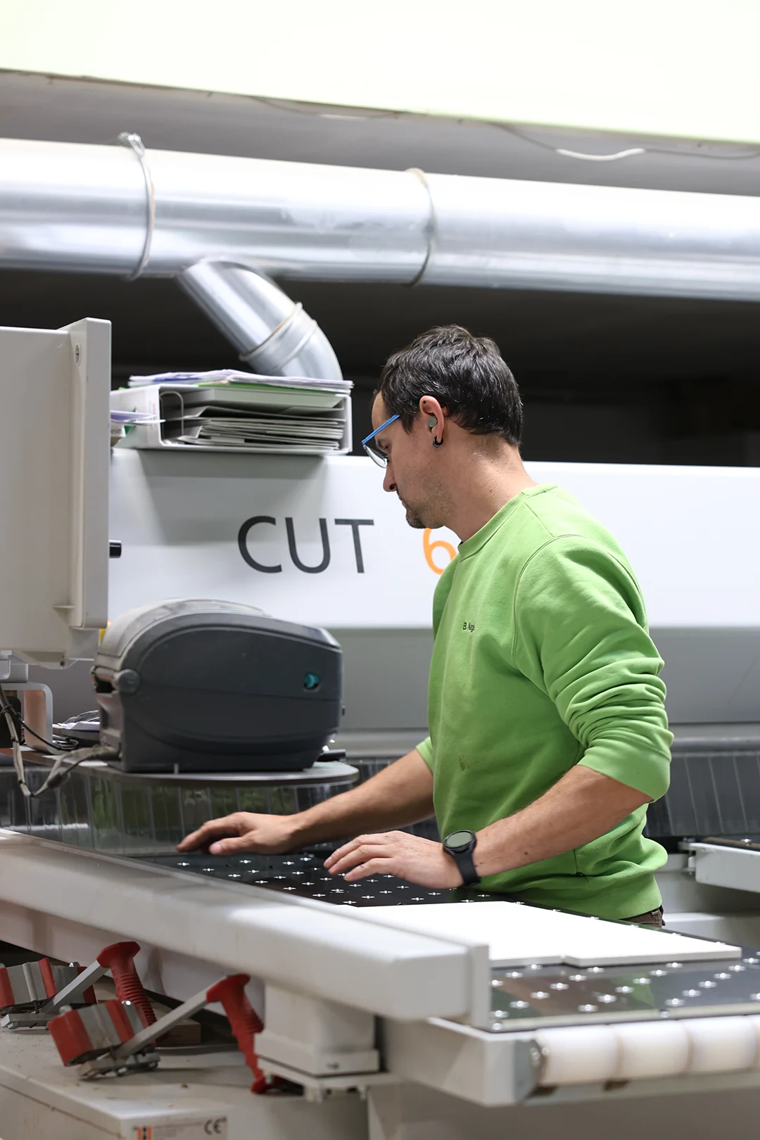 Mitarbeiter bedient CNC-Maschine in moderner Produktionshalle für industrielle Fertigung.